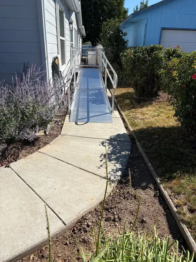 Peak Pro aluminum wheelchair ramp with twin handrails off a side entry, concrete path and lavender in front