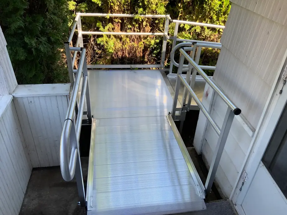 Switchback aluminum ramp with a landing between a house wall and a white fence, installed by Peak Pro